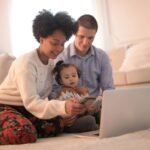 A joyful family of three enjoying togetherness while using a laptop indoors.