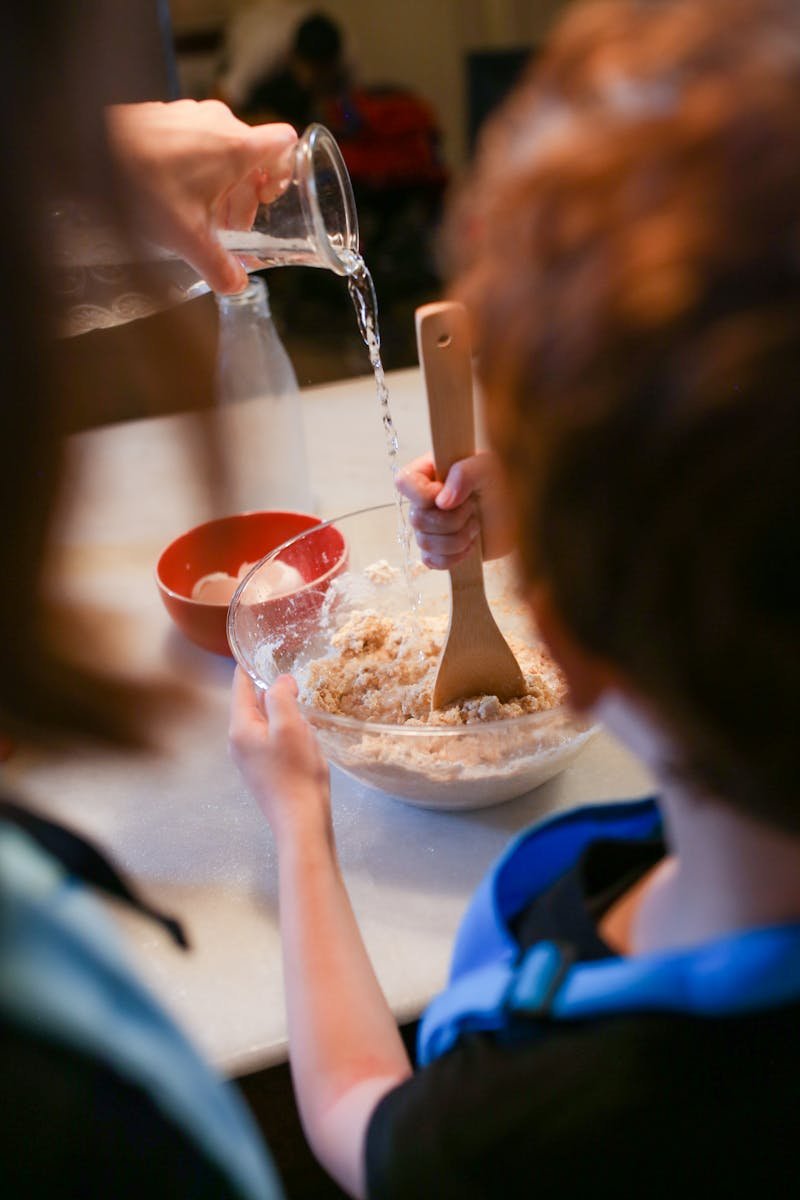 Kids learning and having fun while cooking together in a home kitchen setting.
